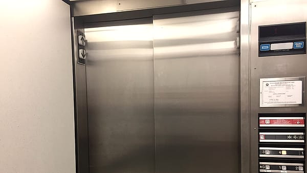 A pair of closed elevator doors in the corridor of a hospital in southern New Hampshire, with the call button beside them