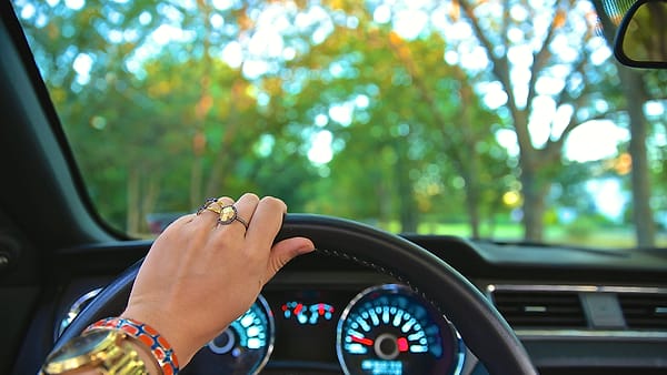 A driver's hand resting on the steering wheel of a car in Medford, Long Island, United States