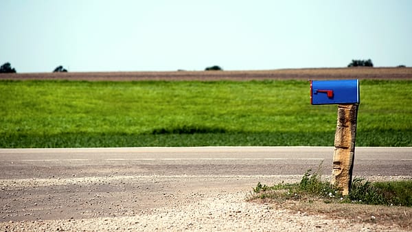 A roadside mailbox standing on its post beside an open road on the Great Plains in Kansas