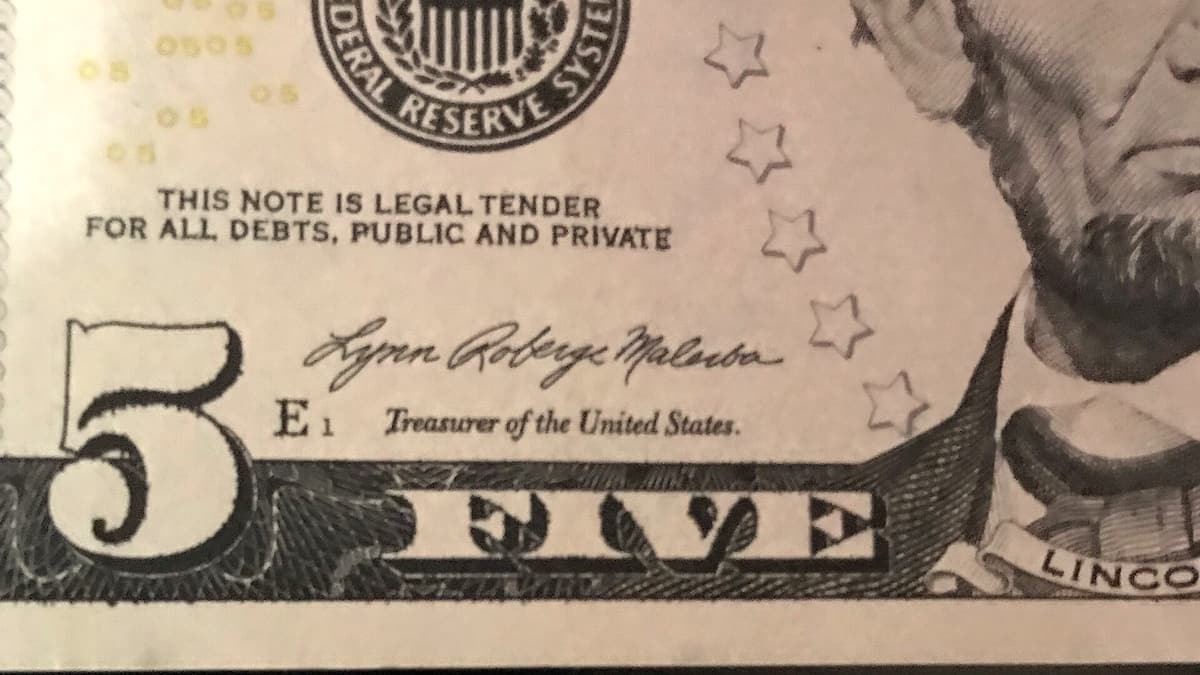 A close view of a United States five-dollar bill showing the engraved signature of the Treasurer
