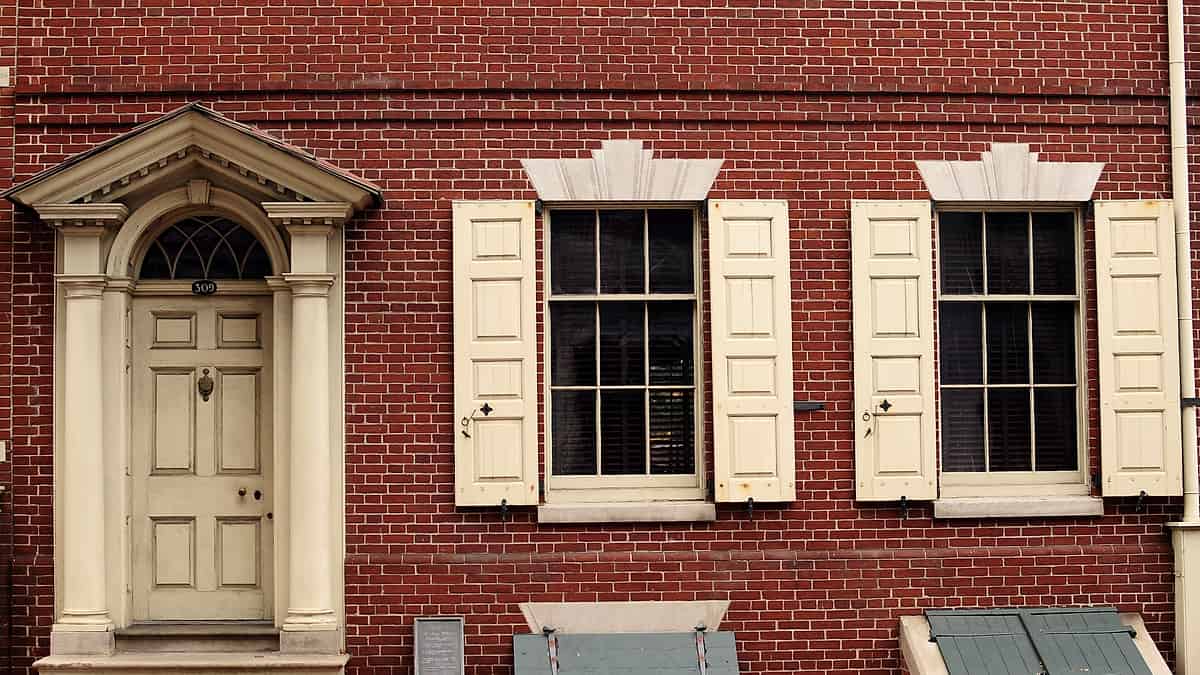 The white front door of the Bishop White House with shuttered first floor windows on either side of it